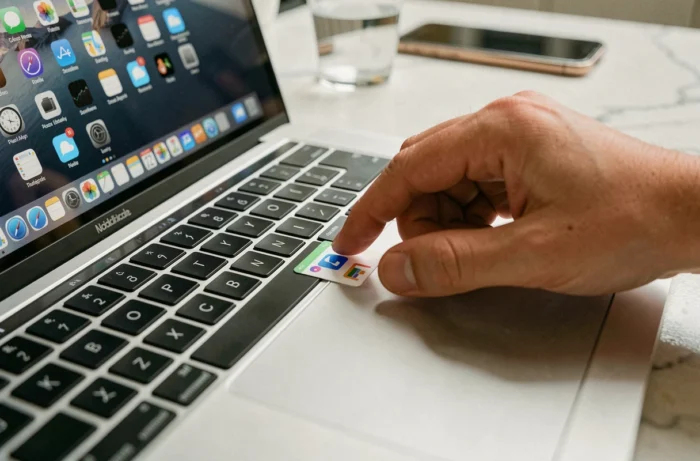 Gros plan d'une main créant un raccourci Le Bon Coin sur le bureau d'un MacBook